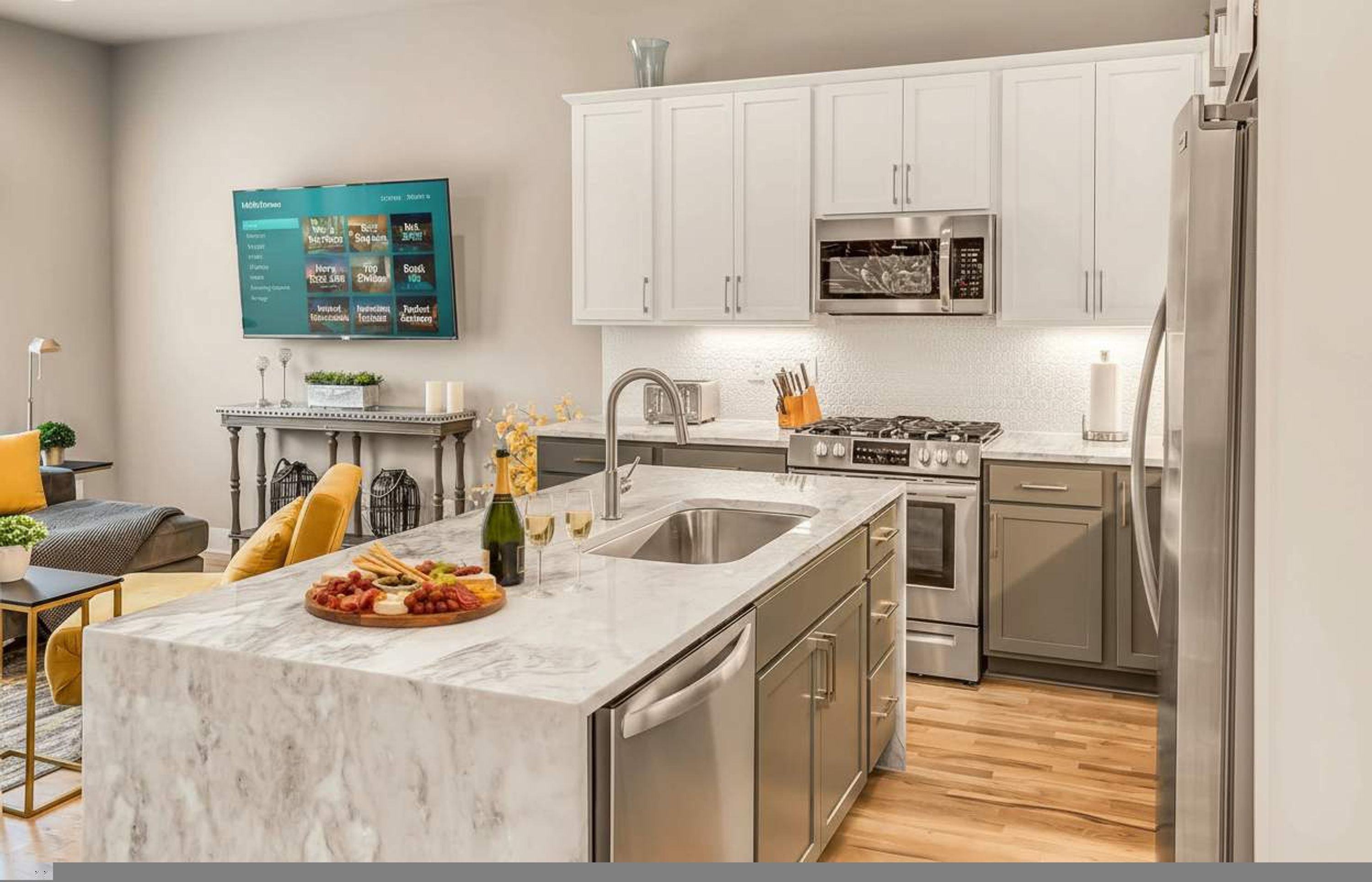 A modern kitchen with white cabinets, stainless steel appliances, a marble countertop, and a built-in oven.