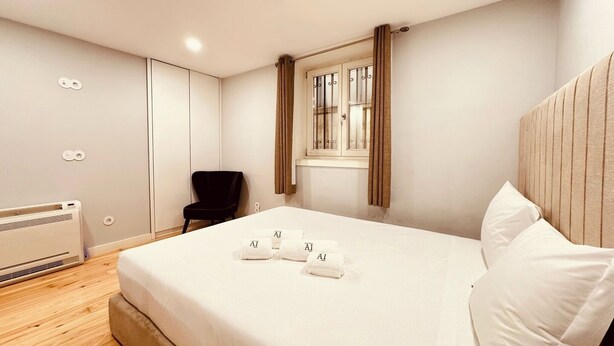 A bedroom with a bed, a chair, a window with curtains, and a radiator. - Torrinha's Backyard ** Porto Center (Porto)