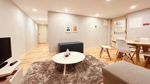 A modern living room with a flat-screen TV, a round coffee table, a sofa, and a dining area with chairs. - Torrinha's Backyard ** Porto Center (Porto)
