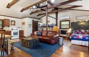 A spacious living room with a leather sofa, wooden coffee table, and a bunk bed with a quilt.