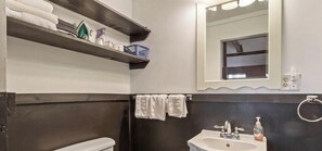 A bathroom with a white sink, dark walls, a mirror, and a towel rack.