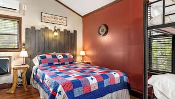A bedroom with a bed, a wooden headboard, a wall clock, and a window with blinds.