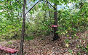 A forested area with a red bench and a trail sign.