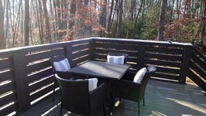 A deck with a table and chairs, surrounded by a wooden railing. - Picturesque Tiny Cottage with Cozy Indoor and Outdoor in Tennessee (Monteagle)