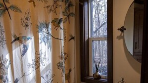 A bathroom with a toilet, sink, and window with a view of trees. - Picturesque Tiny Cottage with Cozy Indoor and Outdoor in Tennessee (Monteagle)