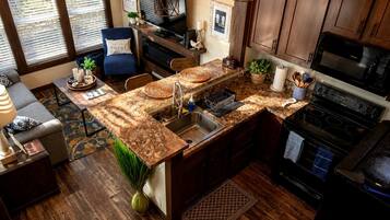 A kitchen with a granite countertop, stainless steel sink, and a black stove.