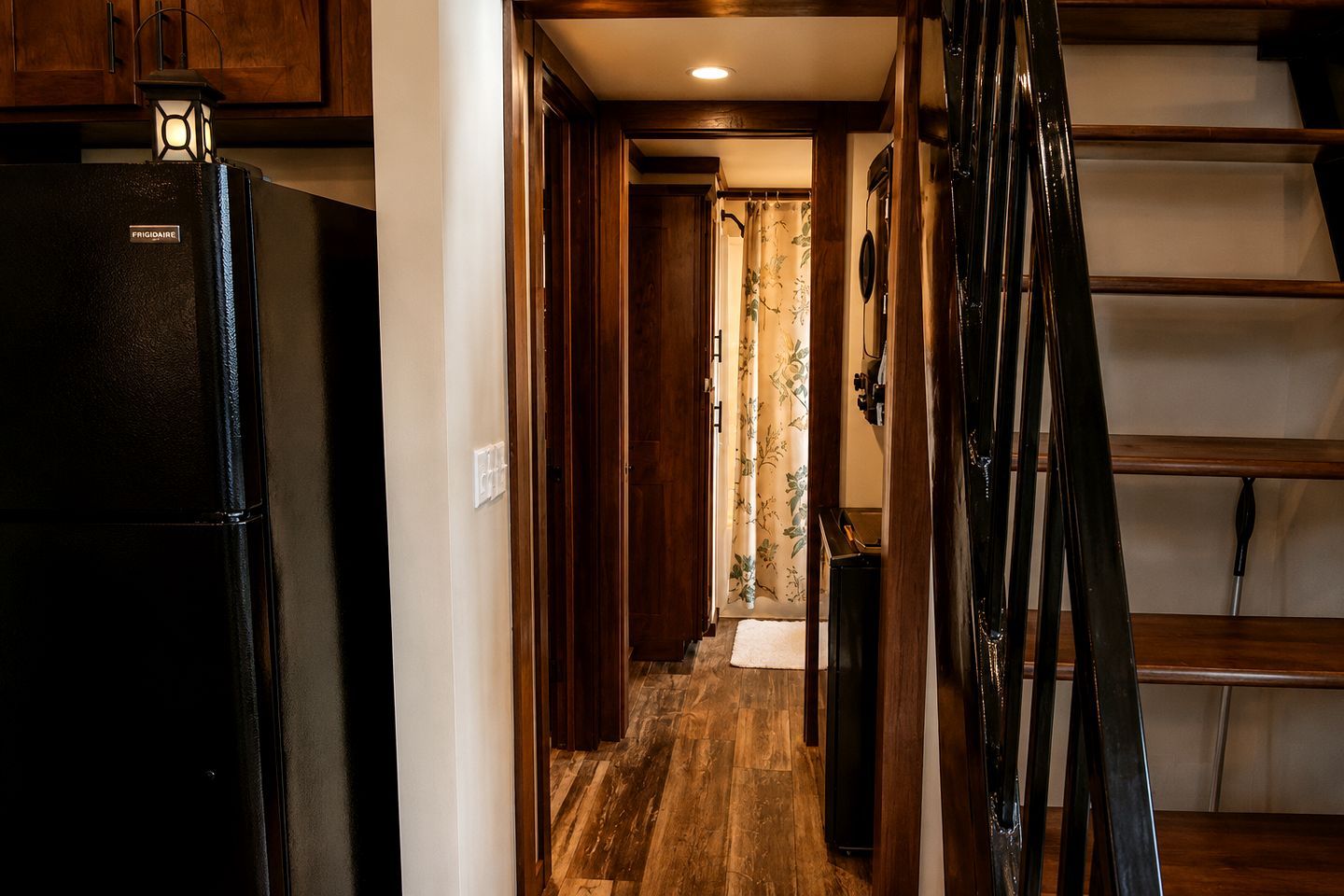 Una cocina con refrigerador, armarios de madera y una escalera.