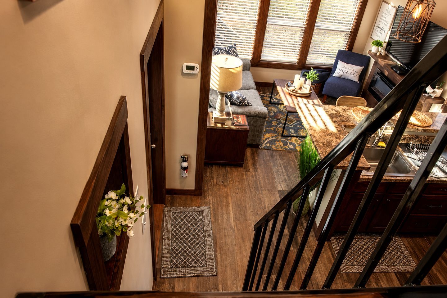 A staircase leading to a living area with a sofa, a lamp, and a dining table.