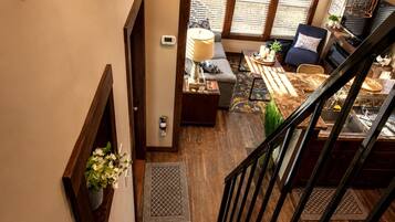 A staircase leading to a living area with a sofa, a lamp, and a dining table.