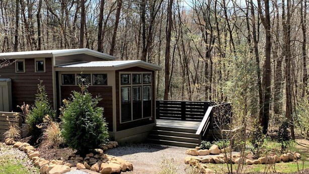 A modern building with a gravel driveway, surrounded by a landscaped garden with rocks and shrubs. - Picturesque Tiny Cottage with Cozy Indoor and Outdoor in Tennessee (Monteagle)