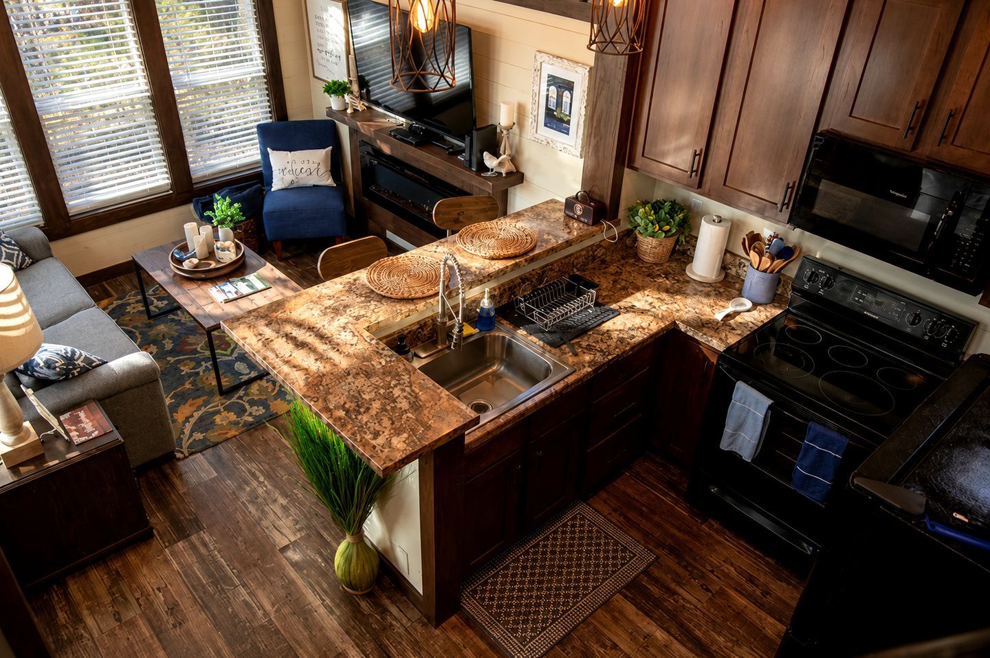 A kitchen with a granite countertop, stainless steel sink, and a black stove.