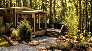 Une cabane dotée d’une terrasse, entourée d’une forêt.
