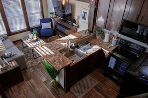 Una cocina moderna con encimeras de granito, horno integrado y una zona de comedor con una silla azul.