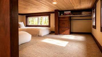 Une chambre avec une grande fenêtre, un lit, une commode et un placard.