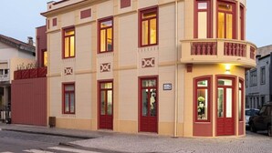 Ein Eckgebäude mit geschwungener Fassade, roten Türen und einem Balkon.