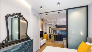 A modern bedroom with a large mirror, a bed with a yellow pillow, and a view into the kitchen area. - Tribunali Trendy Accommodations by Wonderful Italy (Naples)