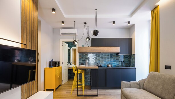 A modern kitchen with a wooden bar counter, a yellow stool, and a built-in TV. - Tribunali Trendy Accommodations by Wonderful Italy (Naples)