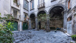 A courtyard with stone paving, a green door, and potted plants. - Tribunali Trendy Accommodations by Wonderful Italy (Naples)