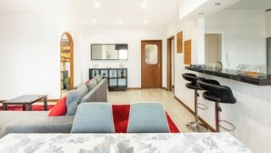 Un salon moderne comprenant un canapé, une table basse et un coin repas avec un bar.