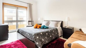 Une chambre d’hôtel moderne dotée d’un grand lit, d’un bureau, d’une chaise, d’une fenêtre avec des rideaux et d’un balcon avec vue.