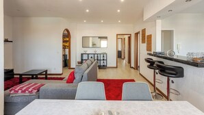 Un salon moderne comprenant un canapé, une table à manger et un coin cuisine avec un comptoir-bar.
