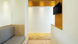 A modern, minimalist room with a wooden bench, a flat-screen TV mounted on a wall, and a carpeted floor. - A'Mar - Room A (Póvoa de Varzim)