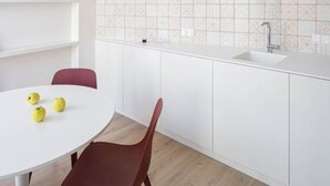 A modern kitchen with white cabinets, a round dining table with chairs, and a patterned backsplash. - A'Mar - Room A (Póvoa de Varzim)