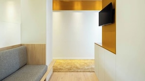 A modern, minimalist room with a wooden bench, a flat-screen TV mounted on a wall, and a wooden floor. - A'Mar - Room D (Póvoa de Varzim)