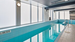 An indoor swimming pool with clear glass walls, a sign indicating a depth of 2 meters, and a tiled floor. - Modern City Convenience With Great Amenities (Melbourne)