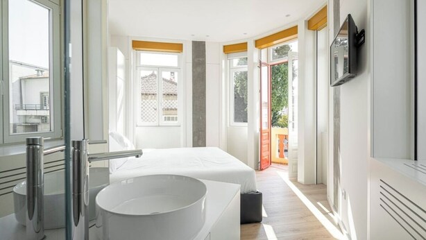 A modern bedroom with a large white bed, a round white sink, and a balcony with orange railings. - A'Mar - Room B (Póvoa de Varzim)