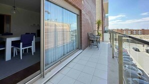 Un appartement moderne doté d’un coin repas, d’un balcon donnant sur la rue et d’une grande porte-fenêtre coulissante.