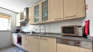 Une cuisine moderne avec des meubles en bois, un lave-vaisselle Bosch, un four à micro-ondes et une cuisinière à gaz.