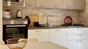 Una cocina moderna con electrodomésticos de acero inoxidable, armarios blancos y salpicadero de azulejos.