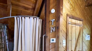 Un intérieur en bois avec une table ronde, deux chaises, un rideau et une porte avec une pancarte.