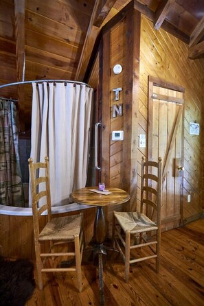 A wooden interior with a round table, two chairs, a curtain, and a door with a sign. - Stunning Wooden Cottage with Hot-tub in Sevierville, Tennessee (Sevierville)