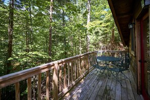A wooden deck with a table and chairs, surrounded by dense forest. - Stunning Wooden Cottage with Hot-tub in Sevierville, Tennessee (Sevierville)