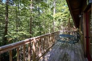 A wooden deck with a table and chairs, surrounded by dense forest. - Stunning Wooden Cottage with Hot-tub in Sevierville, Tennessee (Sevierville)