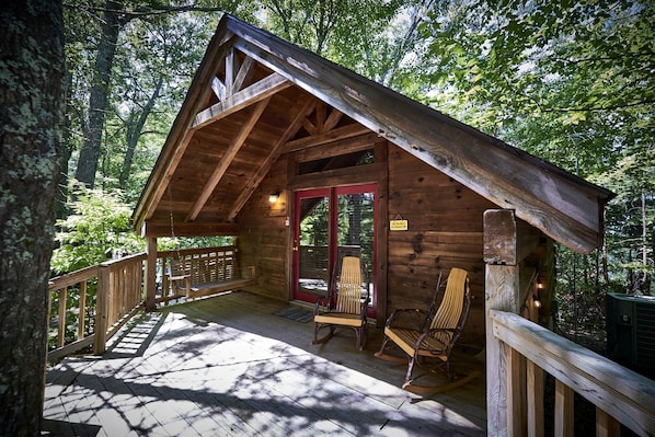 A rustic cabin with a porch, wooden deck, and two rocking chairs. - Stunning Wooden Cottage with Hot-tub in Sevierville, Tennessee (Sevierville)