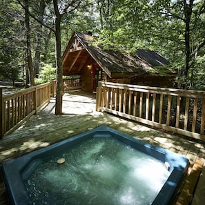 A wooden deck with a hot tub, surrounded by trees and a cabin. - Stunning Wooden Cottage with Hot-tub in Sevierville, Tennessee (Sevierville)