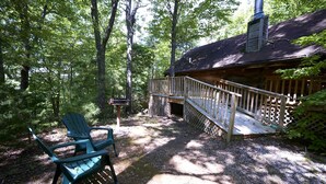 Une cabane avec une terrasse, une chaise et une cheminée.