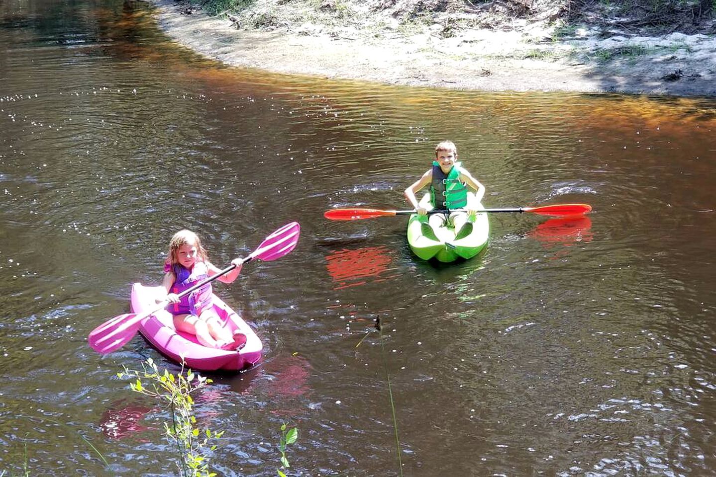 Dos personas haciendo kayak en un río tranquilo.