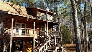 A wooden cabin with a balcony, a staircase, and a deck.