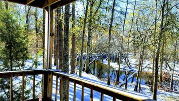 A wooden deck overlooking a snowy forest with a river.
