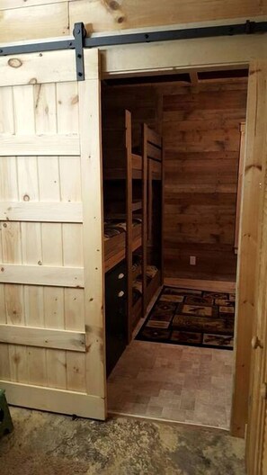 Un intérieur en bois avec une porte coulissante, un banc intégré et un tapis à motifs.