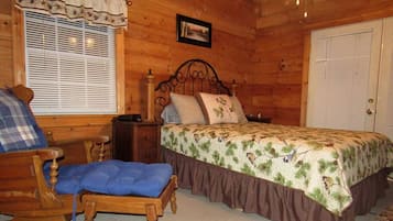 Une chambre à coucher dans un chalet en bois, avec un lit, une chaise, une table de chevet et une fenêtre avec des stores.