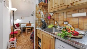 Una cucina compatta con mobili in legno, un lavello e una zona pranzo con tavolo e sedie.