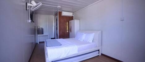A modern bedroom with a bed, a bedside table, a mirror, and a wardrobe.