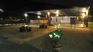 Un espacio al aire libre techado con mesas y sillas, una planta en maceta y un cartel.