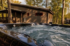 A hot tub with a wooden deck and a building with red-framed windows. - Lakefront Cabin with Two Decks and Back Yard in Tennessee (Tracy City)