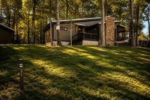 A cabin with a stone exterior, a covered porch, and a grassy yard. - Lakefront Cabin with Two Decks and Back Yard in Tennessee (Tracy City)